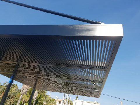 Close view of the edge of a dark aluminum louvre roof and its tension rod
