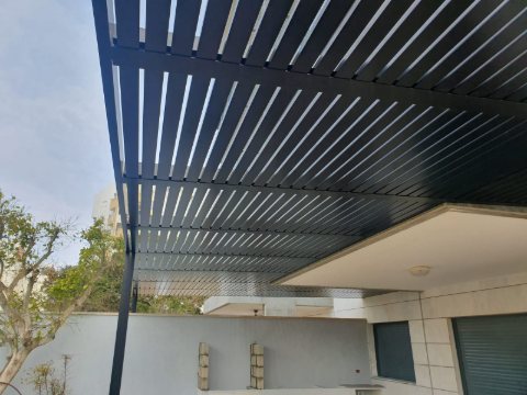 Dark aluminum louvres projecting from a modern house, seen from below