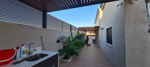 Narrow terrace with an outdoor sink under a slatted aluminum pergola