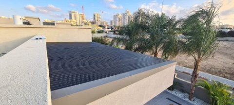 Dark aluminum pergola roof seen from above, set into a rendered parapet