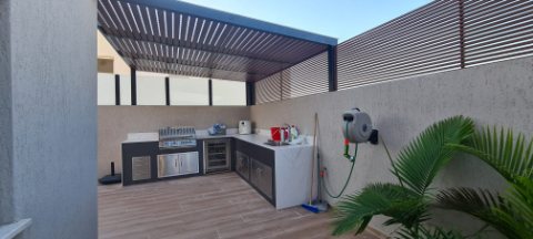 Roof-terrace outdoor kitchen under a wood-look aluminum pergola