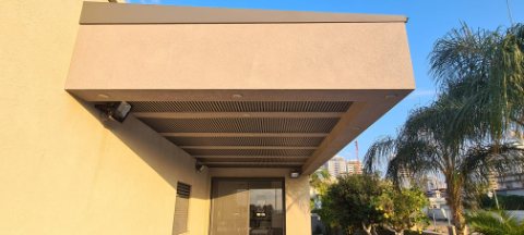 Dark slatted aluminum canopy set into a rendered frame above an entrance