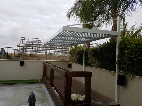 White aluminum pergola on a roof terrace next to a timber bench