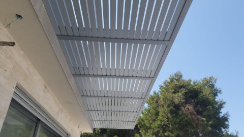 White aluminum slats and beam seen from below against the sky