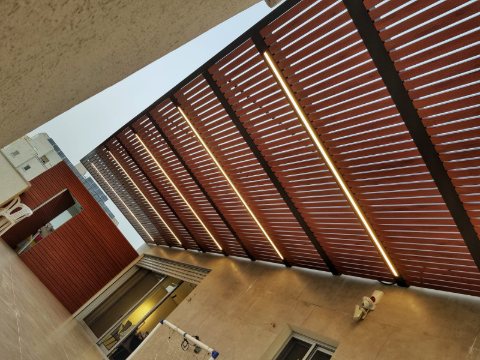 Wood-look aluminum slats with built-in LED strip lights on a dark frame, seen from below